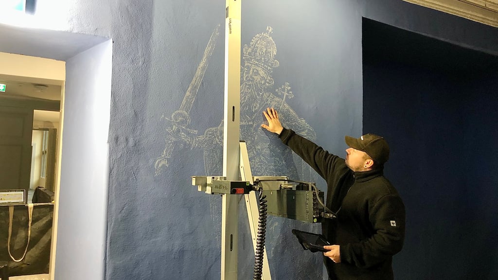 Florian Haase, Projektleiter bei der wallPen GmbH, erklärt, wie das Bildnis Heinrichs I. an die Wand eines Ausstellungsraumes im neuen Museum auf dem Stiftsberg Quedlinburg gedruckt wird.