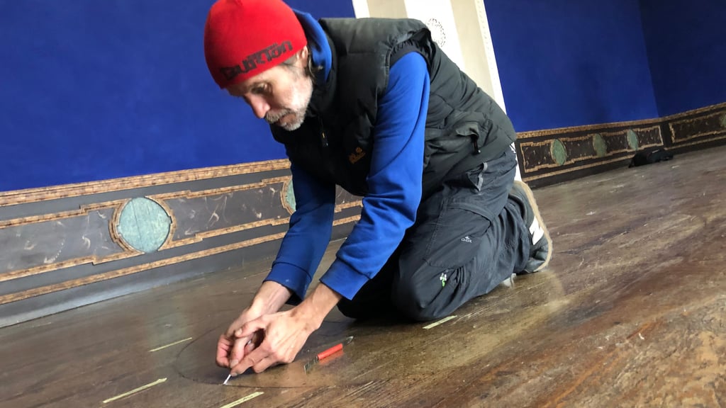 Frank Tangermann reinigt Fugen des historischen Holzbodens im Blauen Saal  auf dem Stiftsberg in Quedlinburg. 