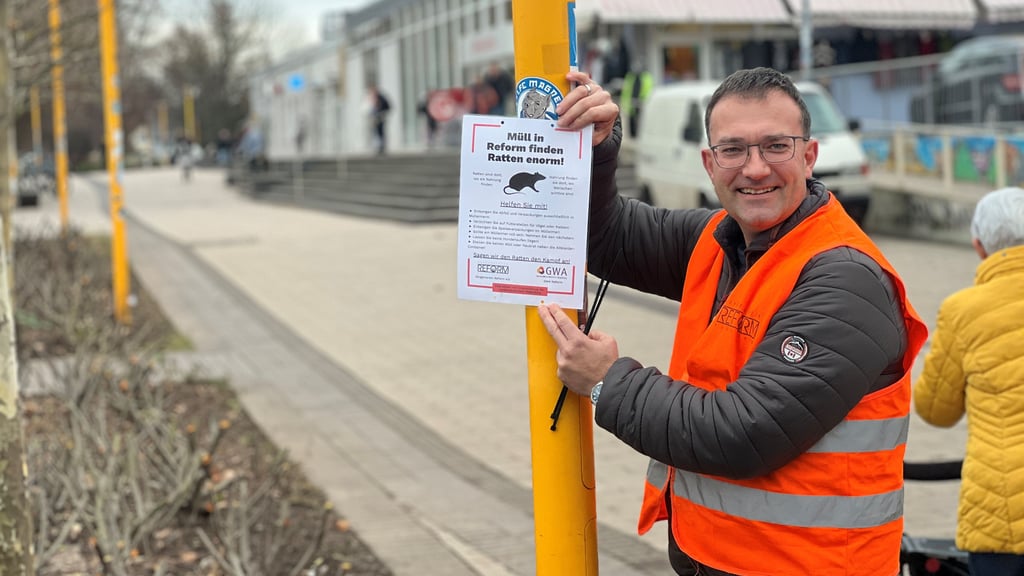 Thomas Siegfried, Vorstandsmitglied des Bürgervereins Reform, bringt die Schilder zum Ratten-Problem an der Kosmospromenade in Magdeburg an. 