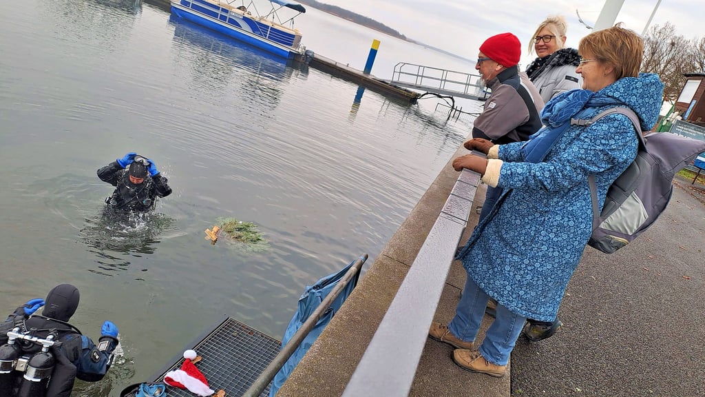 Stephanie und Matthias Metzke bereiten sich auf das Versenken des Weihnachtsbaumes vor – beobachtet von Schaulustigen.