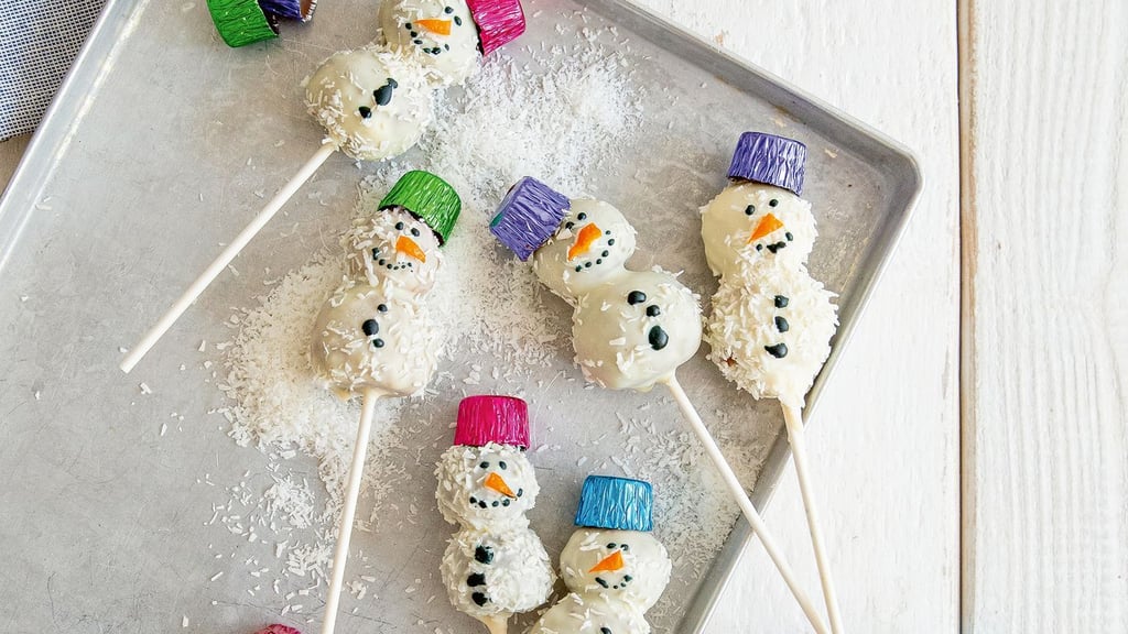 Für die Schneemänner kommt auf jeden Spieß erst eine große Kugel als Schneemannbauch, dann eine kleine Kugel als Kopf. Gesicht und Knöpfe werden mit brauner Zuckerschrift gemalt.