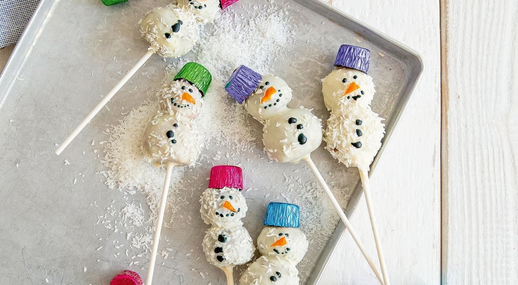 Für die Schneemänner kommt auf jeden Spieß erst eine große Kugel als Schneemannbauch, dann eine kleine Kugel als Kopf. Gesicht und Knöpfe werden mit brauner Zuckerschrift gemalt.