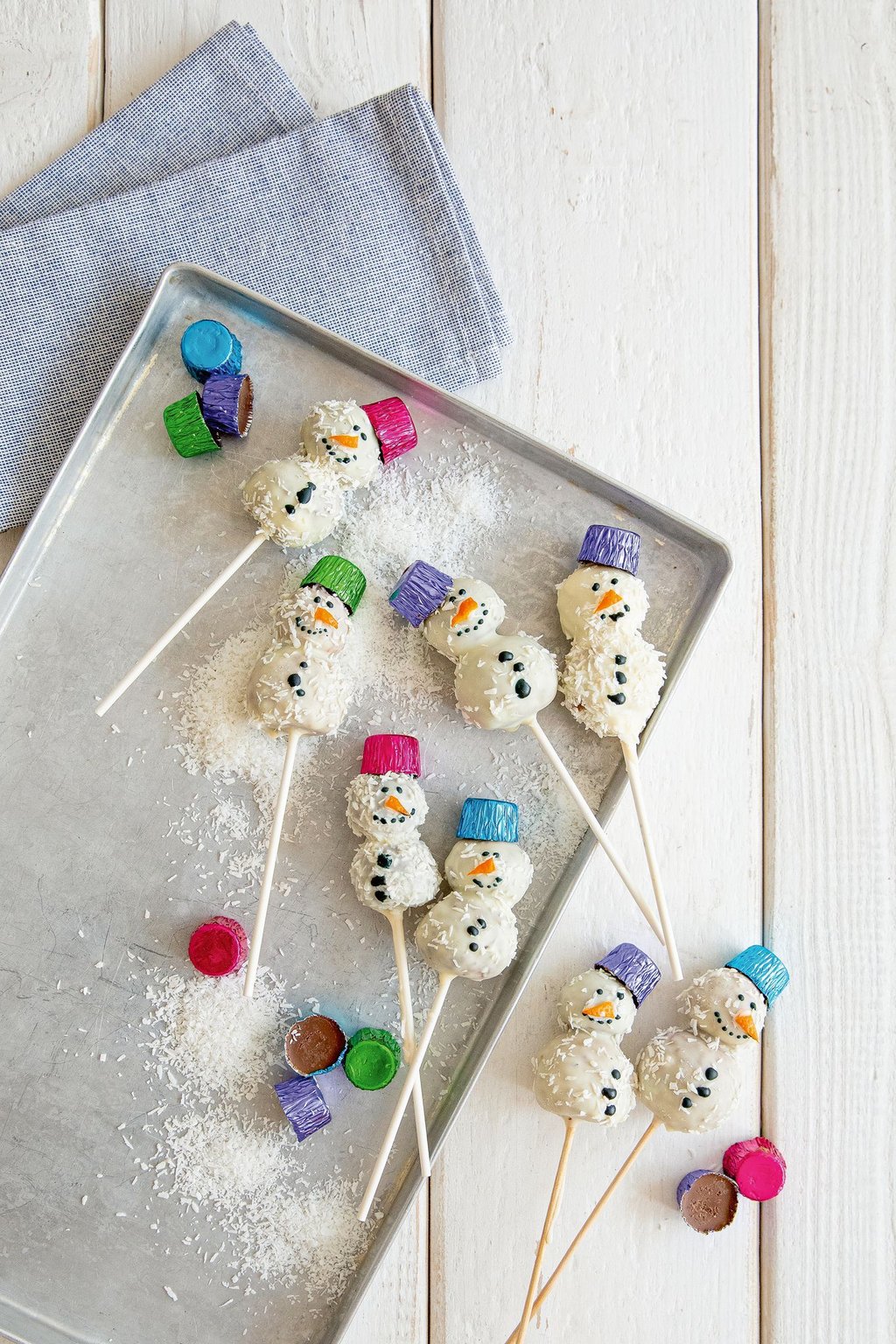 Für die Schneemänner kommt auf jeden Spieß erst eine große Kugel als Schneemannbauch, dann eine kleine Kugel als Kopf. Gesicht und Knöpfe werden mit brauner Zuckerschrift gemalt.