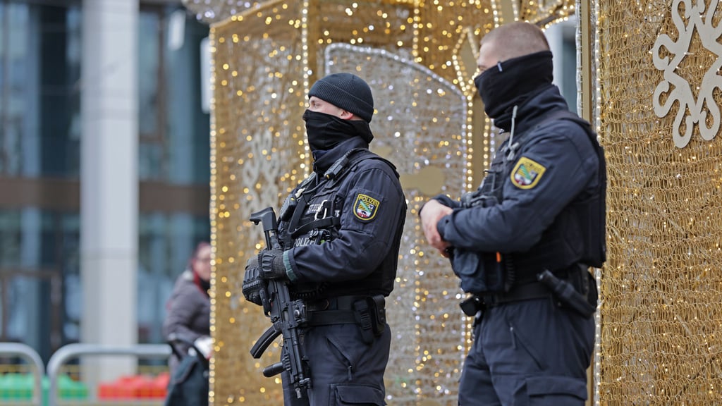 Einsatzkräfte der Polizei stehen auf dem Magdeburger Weihnachtsmarkt. Am ersten Jahrestag des Anschlags auf den Weihnachtsmarkt sichert die Polizei zudem eine Reihe von Gedenkveranstaltungen.