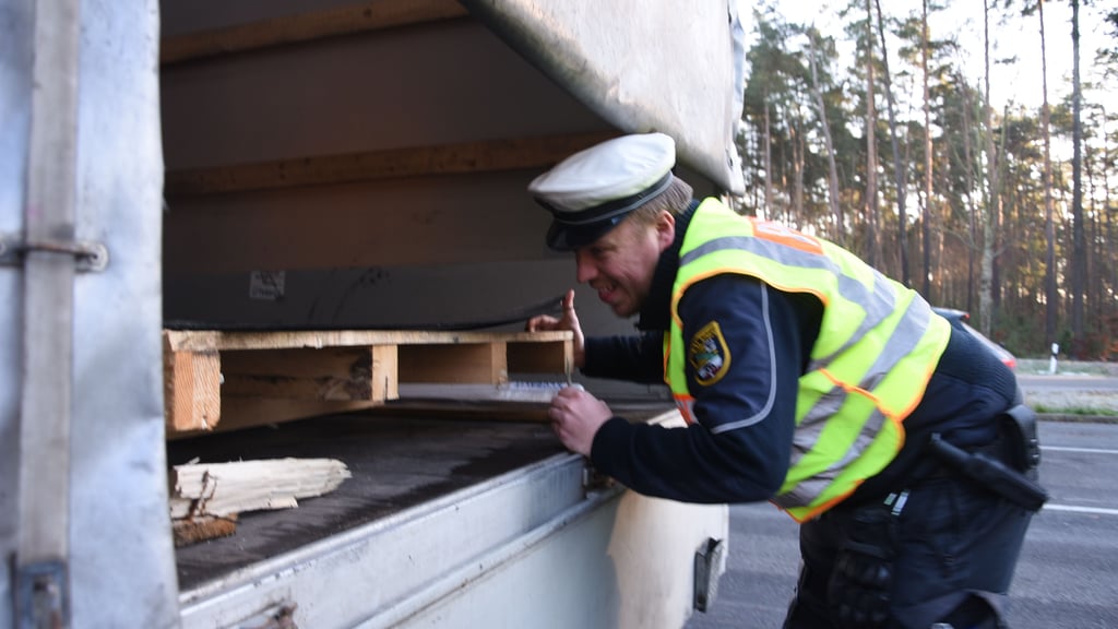 Roadpol-Kontrolle am Parkplatz Langer Heinrich an der B71: Das Bild zeigt Polizeiobermeister Fabian Tiaden, wie er mit vollem Körpereinsatz prüft, ob eine Ladung richtig gesichert ist.
