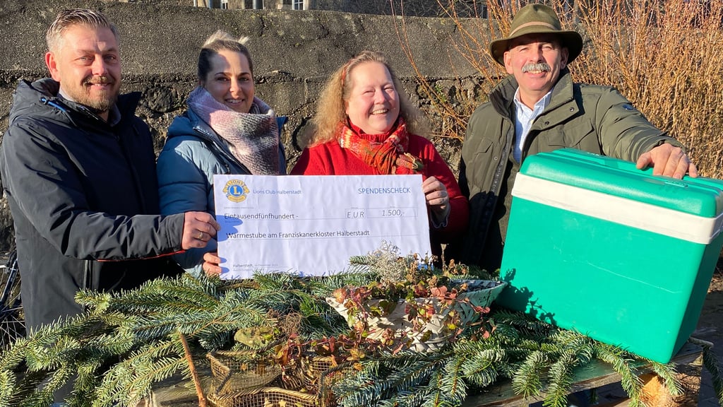 Matthias Hentschel (links) und Friedrich Baumgärtel (rechts) überreichen für den Halberstädter Lions Club an Nancy Kubacki (zweite von links) und Cathleen Brand einen symbolischen Scheck und eine Überraschung für die Wärmestube Halberstadt.