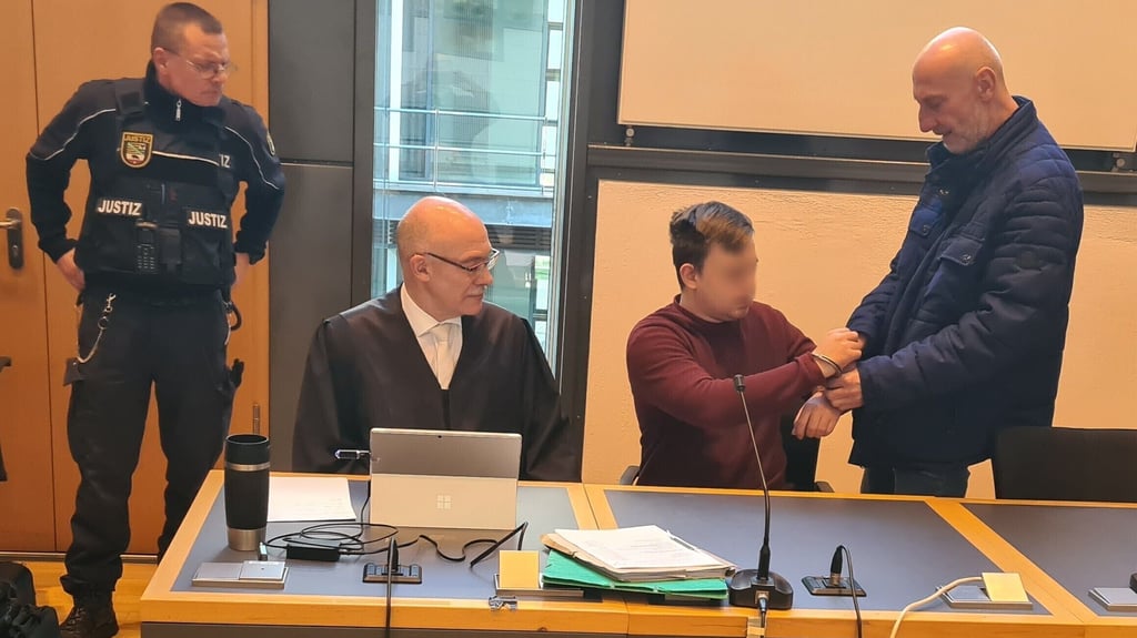 Dem Beschuldigten Richard G. (2. v. r.) werden von einem Mitarbeiter des Maßregelvollzugs Uchtspringe im Gerichtssaal die Handfesseln abgenommen. (2. v. l.) sein Anwalt Thomas Breiter.