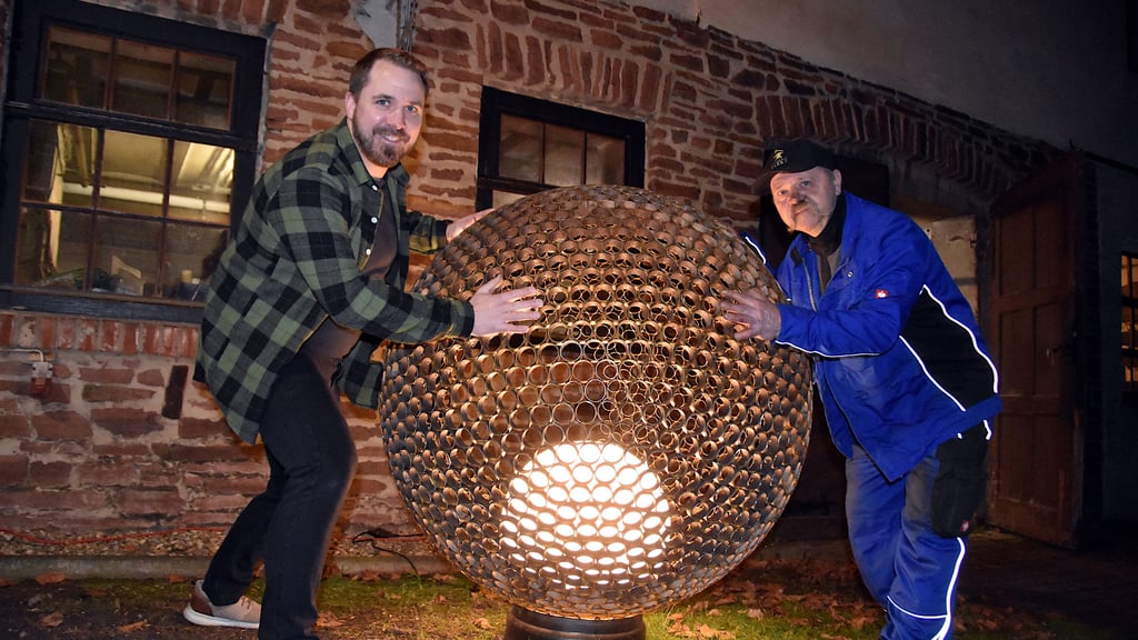Christian (l.) und Reinhard Waeke präsentieren ihre leuchtende Feuerkugel vor der Werkstatt – Kunst aus Stahl, die im Inneren mit einer Lampe oder auch mit echtem Feuer zum Strahlen gebracht wird.