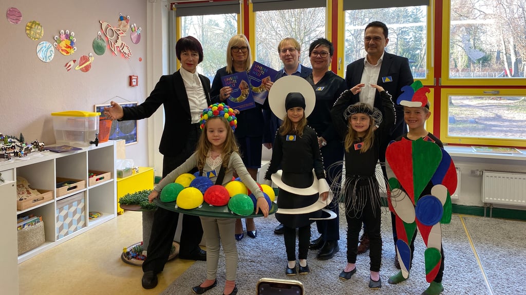 Carmen Niebergall (l.), Christoph Keil (ab 3. v. l.), Carola Hoppe, Thomas Glückstein und die Kitakinder in ihren Bauhaus-Ballettkostümen überreichten die Projektbroschüre an Oberbürgermeisterin Simone Borris (2. v. l.)