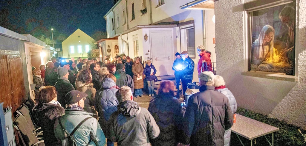 Helmut Szulczynski (mit Licht) öffnet seine Tür beim lebendigen Adventskalender.