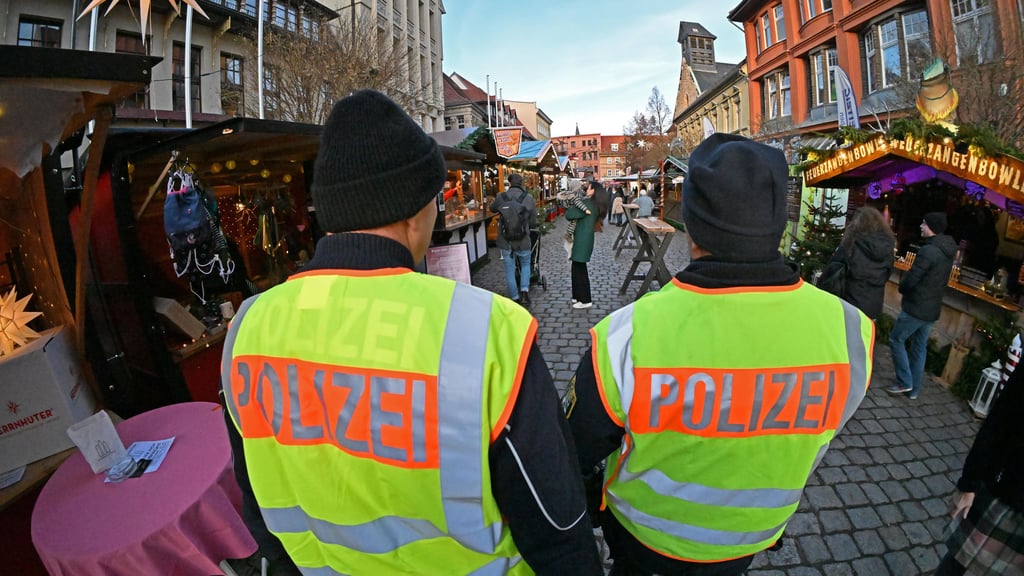 Polizisten sichern den Weihnachtsmarkt in Aschersleben. Landesweit steigen die Kosten für Sicherheitsmaßnahmen.