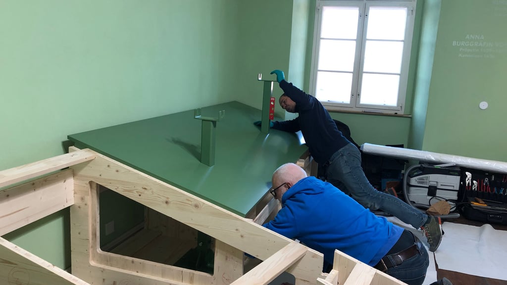 Mitarbeiter des mit der Exponateinrichtung beauftragten Unternehmens „Fißler & Kollegen“ montieren Halterungen an dem Podest, auf dem das erste Ausstellungsobjekt im neuen Museum auf dem Stiftsberg Quedlinburg platziert werden soll.