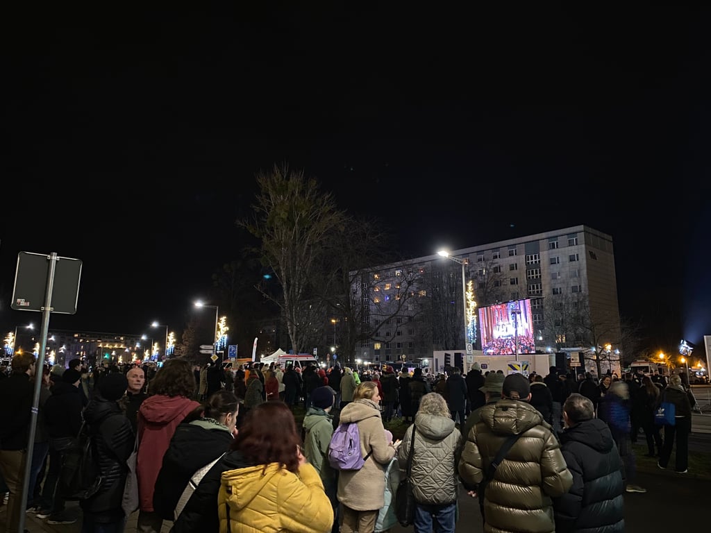 Zahlreiche Menschen schauen sich die Gedenkstunde von draußen an.