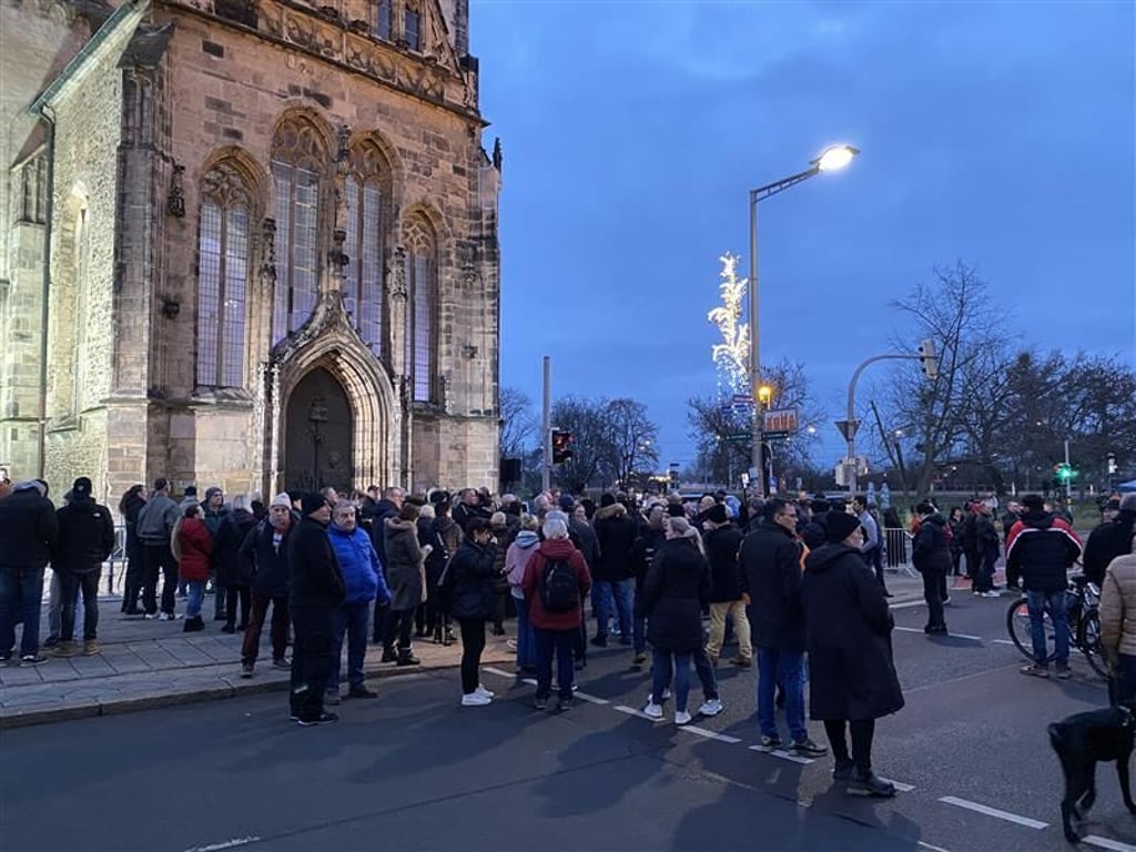 Zur Kranzniederlegung der AfD haben sich zahlreiche Menschen vor der Johanniskirche versammelt.