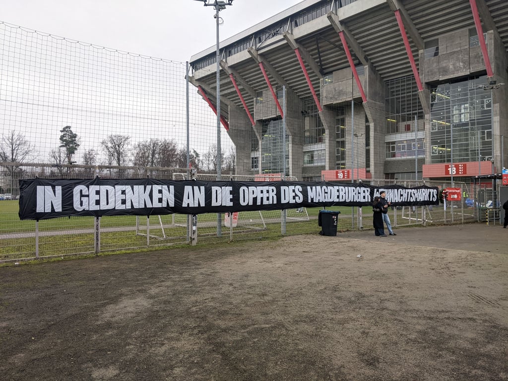FCM spielt gegen Kaiserslautern: Vor dem Einlass zum Gästeblock hängt ein großes Banner&nbsp; samt Blumengesteck.