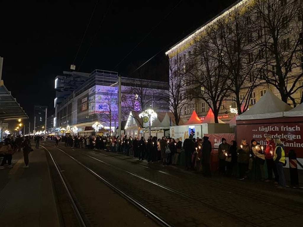 Menschen stellen sich in Magdeburg zum stillen Gedenken in einer Lichterkette auf.