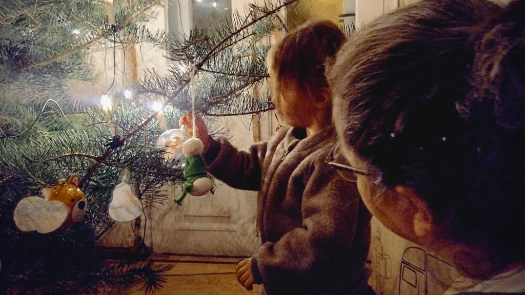 Es gibt Dinge, die bleiben wohl an Weihnachten immer gleich: Baum schmücken udn Kinderuagen, die mit den Lichtern am Baum um die Wette leuchten.