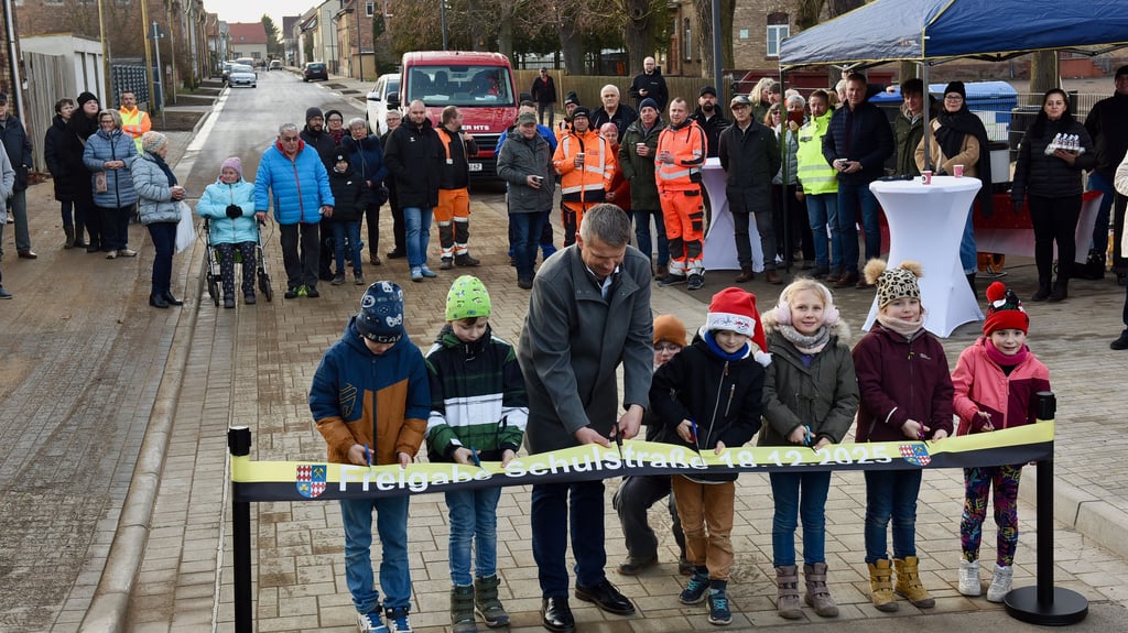 Mit dem Bürgermeister Frank Ochsner schneiden die Kinder das Band in der Klostermansfelder Schulstraße durch.