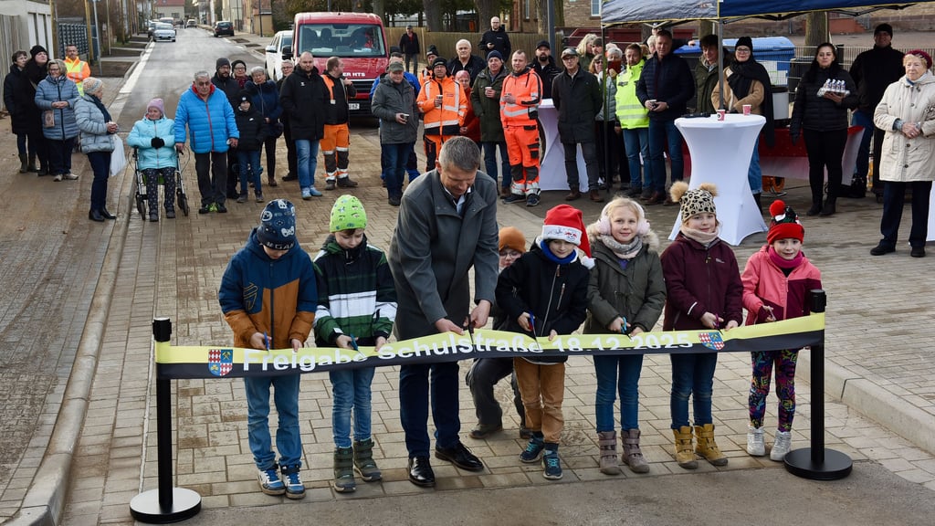Mit dem Bürgermeister Frank Ochsner schneiden die Kinder das Band in der Klostermansfelder Schulstraße durch.