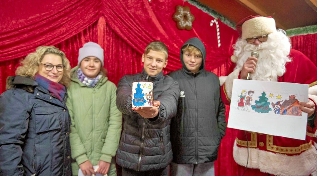 Toni Linhard zeigt stolz die Adventsmarkttasse für 2026 mit seinem Motiv. Links neben ihm die Drittplatzierte Jasmin Krauße.