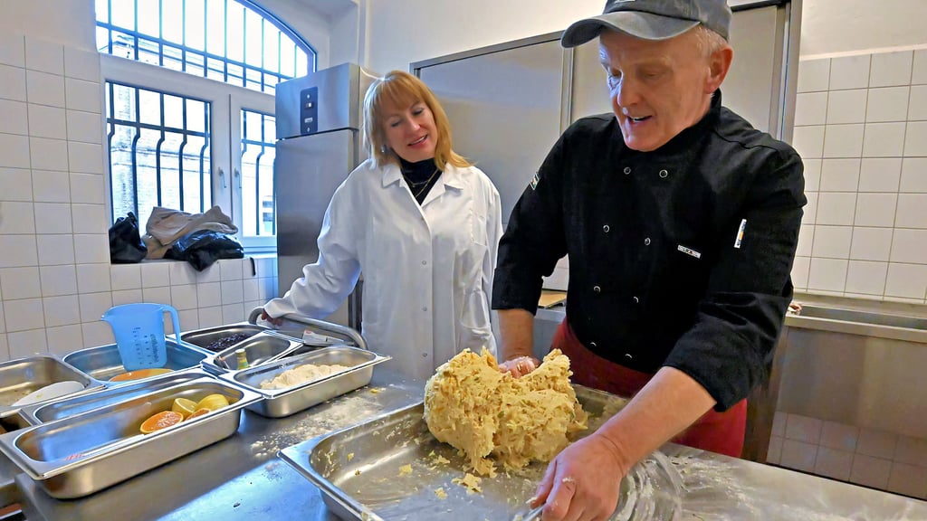 Katja Ziegler von der Salzlandsparkasse schaut Gerd Schmidt, dem Koch der Schloß Hoym Stiftung, beim Backen der Stollen genau über die Schultern.