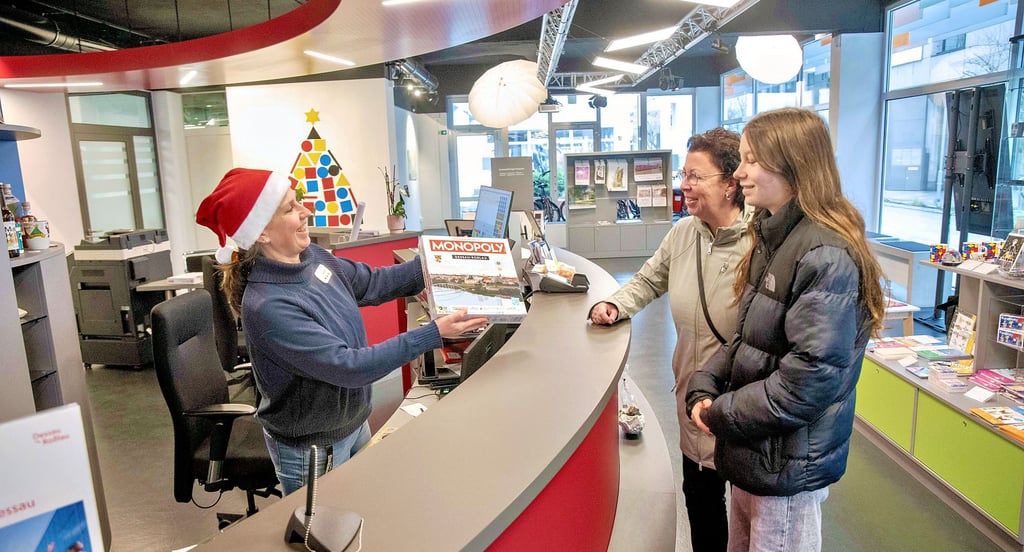 Julia Geupel verkauft in der Tourist-Information ein Dessau Monopoly an Kerstin und Lena Görg.