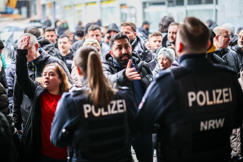 Aufgebrachte Kunden diskutieren vor der Sparkassenfiliale in Buer mit Polizeibeamten nach der Räumung des Vorraums der Filiale.