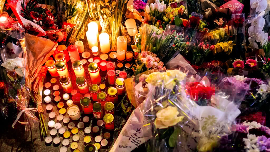 Ein Blumen- und Kerzenmeer erinnert an Tote und Verletzte in der Nähe des Brandortes.