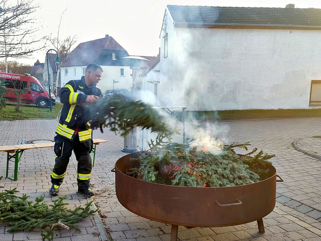 Dominik Schneider legt trockene Weihnachtsbäume in die Feuerschale der Feuerwehr Beesenlaublingen.