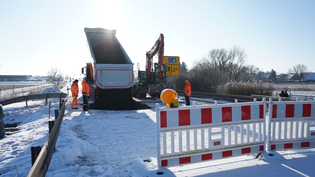 Die Straßendecke auf der B189 bei Wolmirstedt wird provisorisch mit Fräsgut verfüllt. Darauf werden Stahlplatten befestigt.