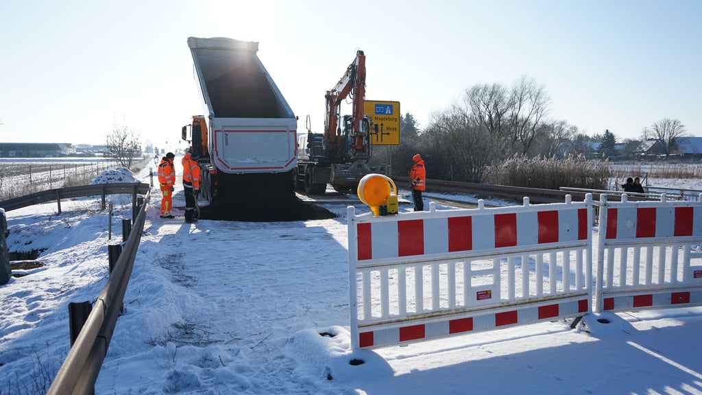 Die Straßendecke auf der B189 bei Wolmirstedt wird provisorisch mit Fräsgut verfüllt. Darauf werden Stahlplatten befestigt.