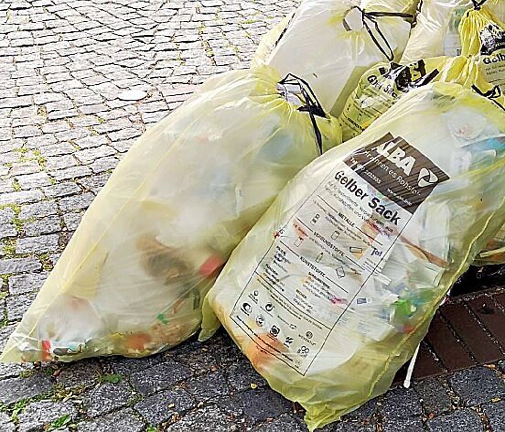 Gelbe Säcke  liegen an der Bordsteinkante einer Straße.
