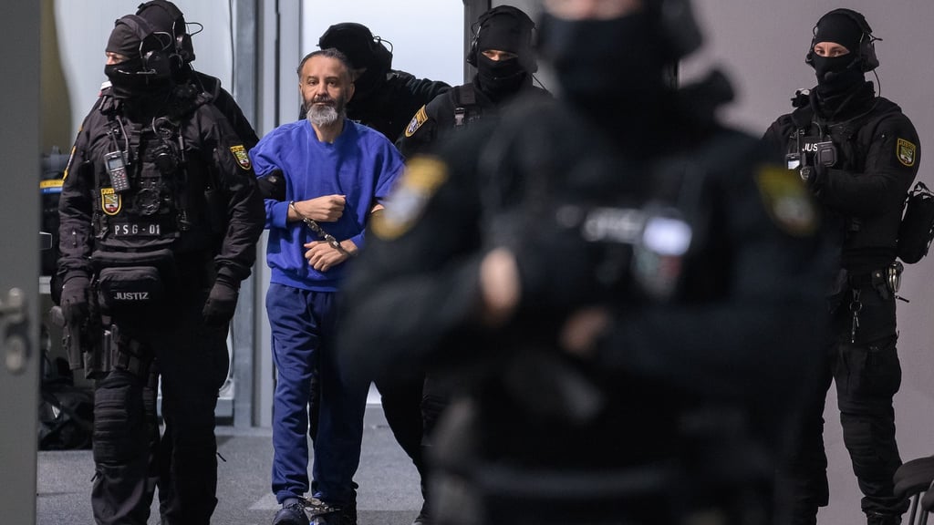 Justizbeamte führen den Angeklagten Taleb al-Abdulmohsen in den Gerichtssaal des temporären Gerichtsgebäudes vom Landgericht Magdeburg.