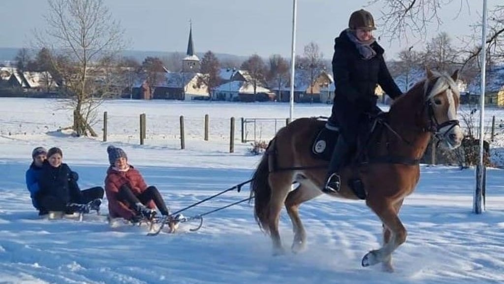 Auf dem verschneiten Gelände des Reiterhofes Schlubeck in Bülstringen sitzt Dörte Wohlsdorf hoch zu Ross und zieht die Schlitten durch den frischen Schnee. Ida Leberecht (auf den beiden Schlitten von vorn nach hinten), Greta von Zelewski und Antje Rieke – eingemummelt in warme Kleidung und sichtbar voller Begeisterung – lassen sich von einer Pferdestärke ziehen. 