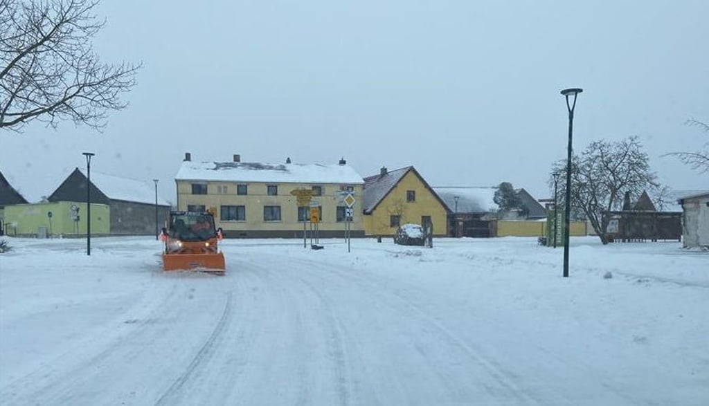 Blick auf die Dorfstraße in Schartau, auf der ein Räumfahrzeug vom Bauhof in Burg im Einsatz ist.