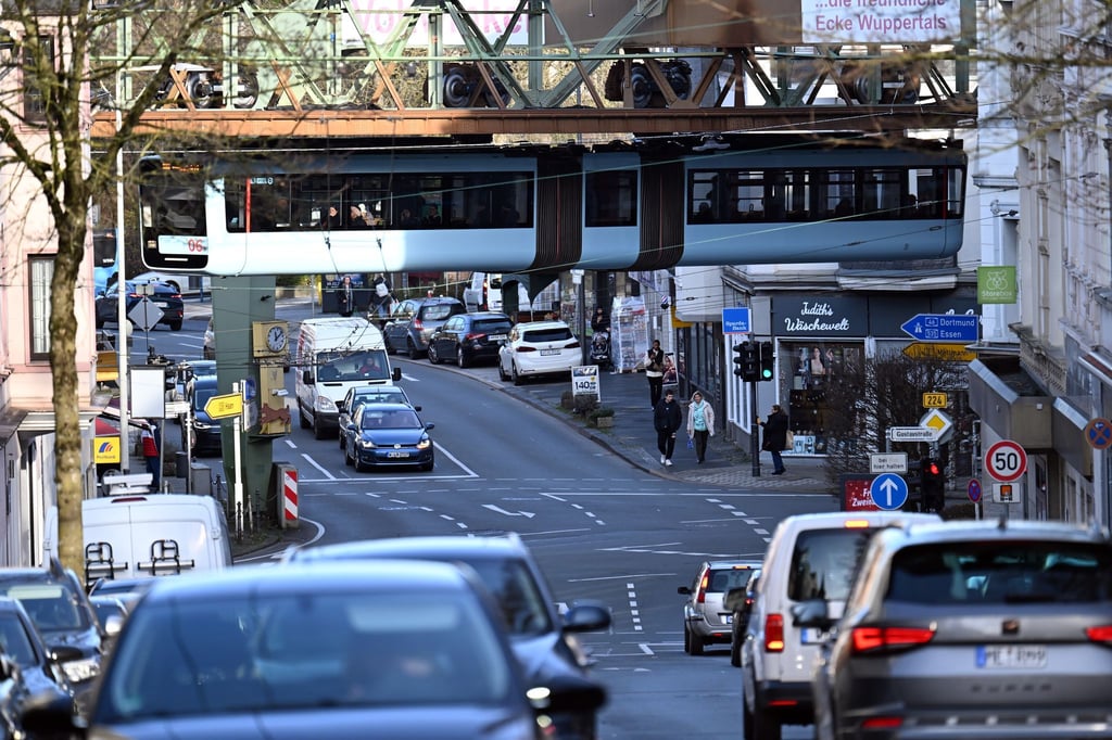 Ein Wagen der Schwebebahn fährt über dem Wuppertaler Straßenverkehr.