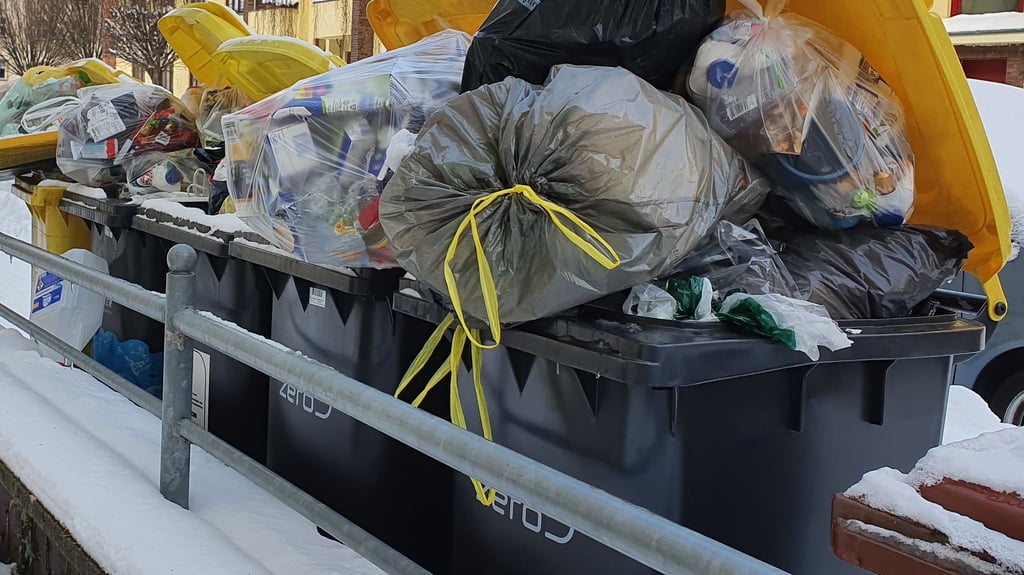 Gelbe Tonnen warten im Schnee auf ihre Abholung.