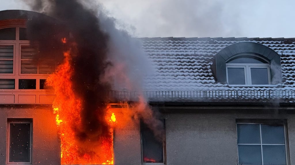 Feuer schlägt während eines Brandes aus dem Fenster eines Hauses.