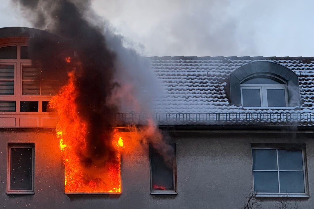 Feuer schlägt während eines Brandes aus dem Fenster eines Hauses.