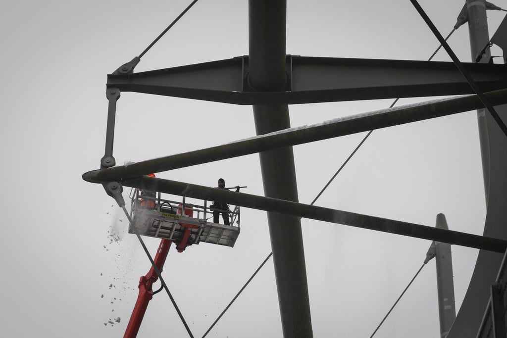 Arbeiter mit einem Hubsteiger entfernen Eis und Schnee von den Trägern des Stadiondachs in Hamburg.