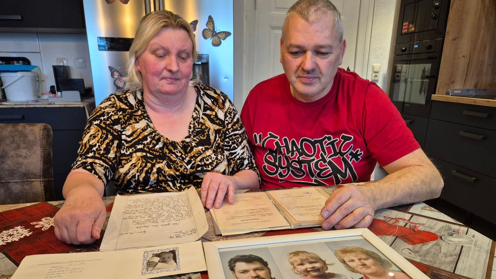 Andrea und Falk Voß sehen sich die alten Unterlagen an. Auf dem Familienfoto ist Falk Voß Mitte 20. "Vielleicht sieht Patrik so ähnlich aus", hoffen sie.