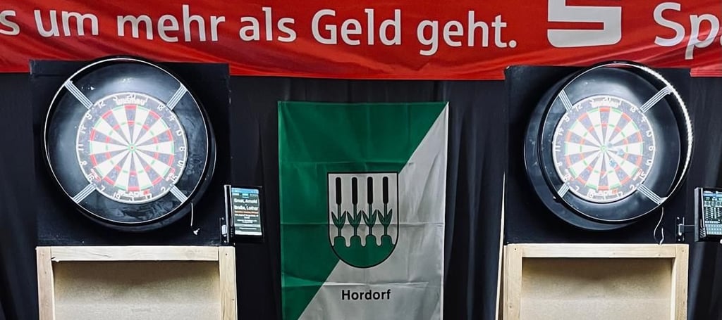 Der Fokus von Teilnehmern und Publikum liegt auf den Dartscheiben.