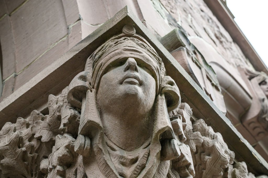 Ein Mann stirbt unerwartet im Amtsgericht Oldenburg. Eine Skulptur der Justitia hängt an einer Säule an dessen Eingang. (Symbolbild)