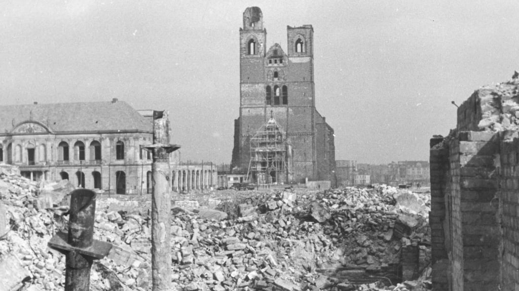Blick auf Trümmer der Innenstadt Magdeburgs mit Rathaus und Johanniskirche.