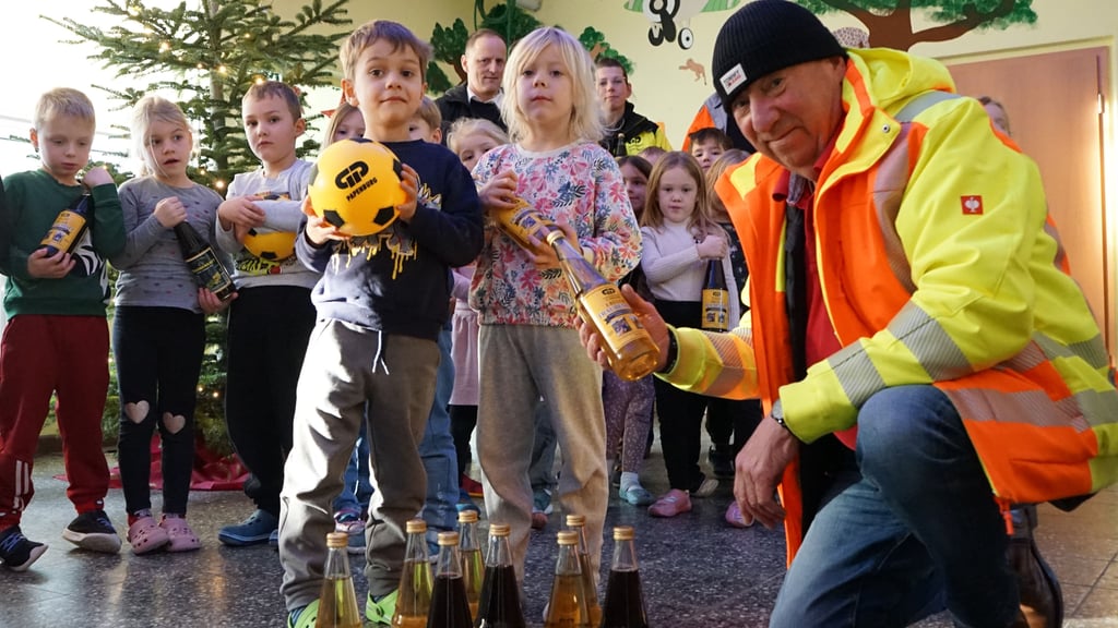 Carlo Hinze, Farsleber Niederlassungsleiter der Firma Papenburg, übergibt Traubensaft an die Kinder der Colbitzer „Storchenwiese“.
