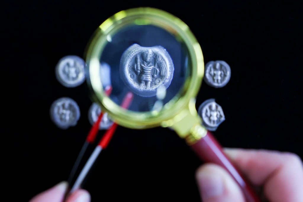 Mittelalterliche Silbermünzen aus dem 12. Jahrhundert unter einer Lupe.