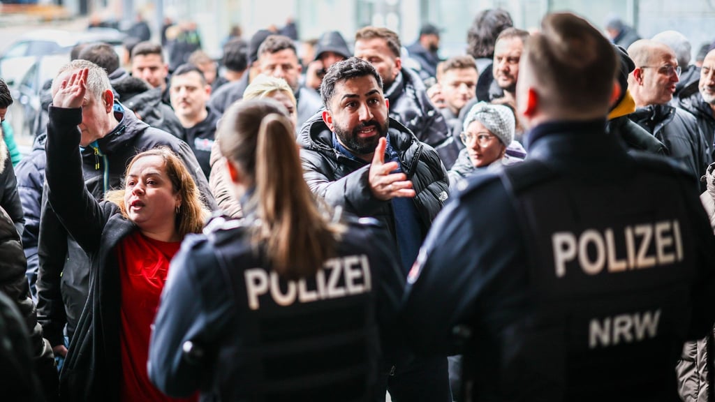 Aufgebrachte Kunden diskutieren vor der Sparkassenfiliale mit Polizeibeamten (Archivfoto)