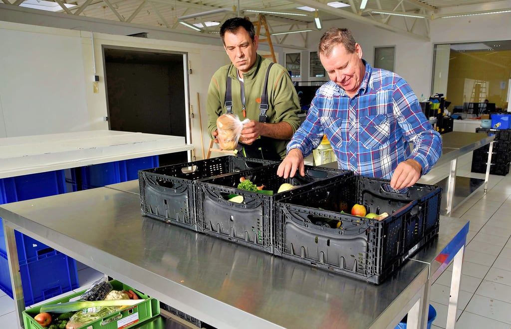 Daniel Schwarzer sortiert mit Tafel-Leiter Ronald Kurek (r.) Kisten mit Lebensmitteln für Bedürftige. Hinten links befindet sich die neue Kühlzelle.