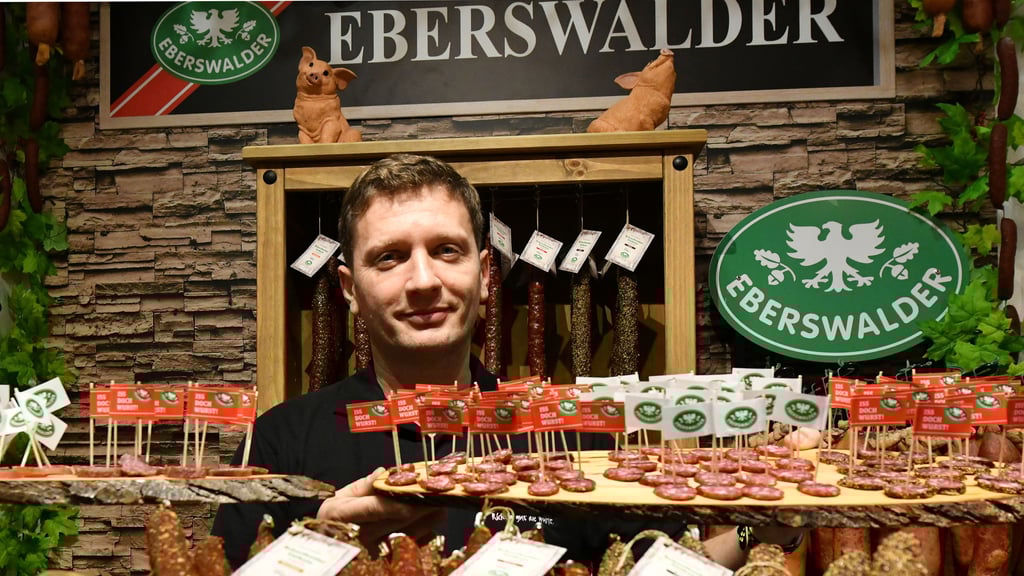Ein Mitarbeiter stellt Eberswalder Salamispezialitäten auf der Grünen Woche vor.