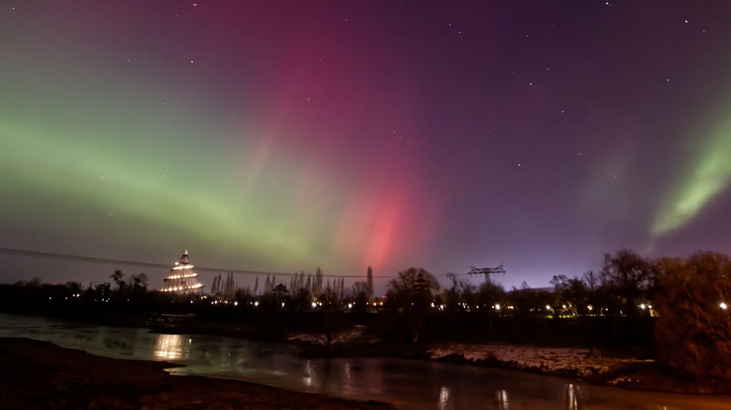 Polarlichter über dem Jahrtausendturm und der Alten Elbe in Magdeburg, fotografiert von der Friedensbrücke in Richtung Norden.